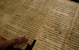 An Israel Museum worker points at the word "Jerusalem" written in a part of the Isaiah Scroll, one of the Dead Sea Scrolls, inside the vault of the Shrine of the Book building at the Israel Museum in Jerusalem, Monday, Sept. 26, 2011. Two thousand years after they were written and decades after they were found in desert caves, some of the world-famous Dead Sea Scrolls are available online. Israel's national museum and the international web giant Google are behind the project, which saw five scrolls go online Monday. (AP Photo/Sebastian Scheiner)